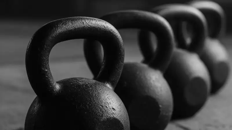 A row of black cast iron kettlebells on concrete